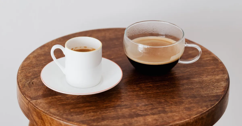 An espresso cup and mug of coffee on a wooden tray, representing the differences between focused go-to-market strategies and broader marketing strategies in growing a climate tech business